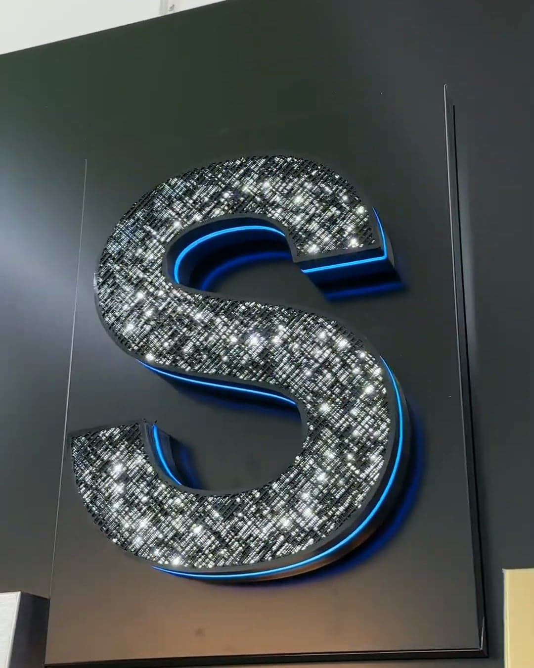 The same letter S finished and lit, its sparkle face glowing with a blue edge