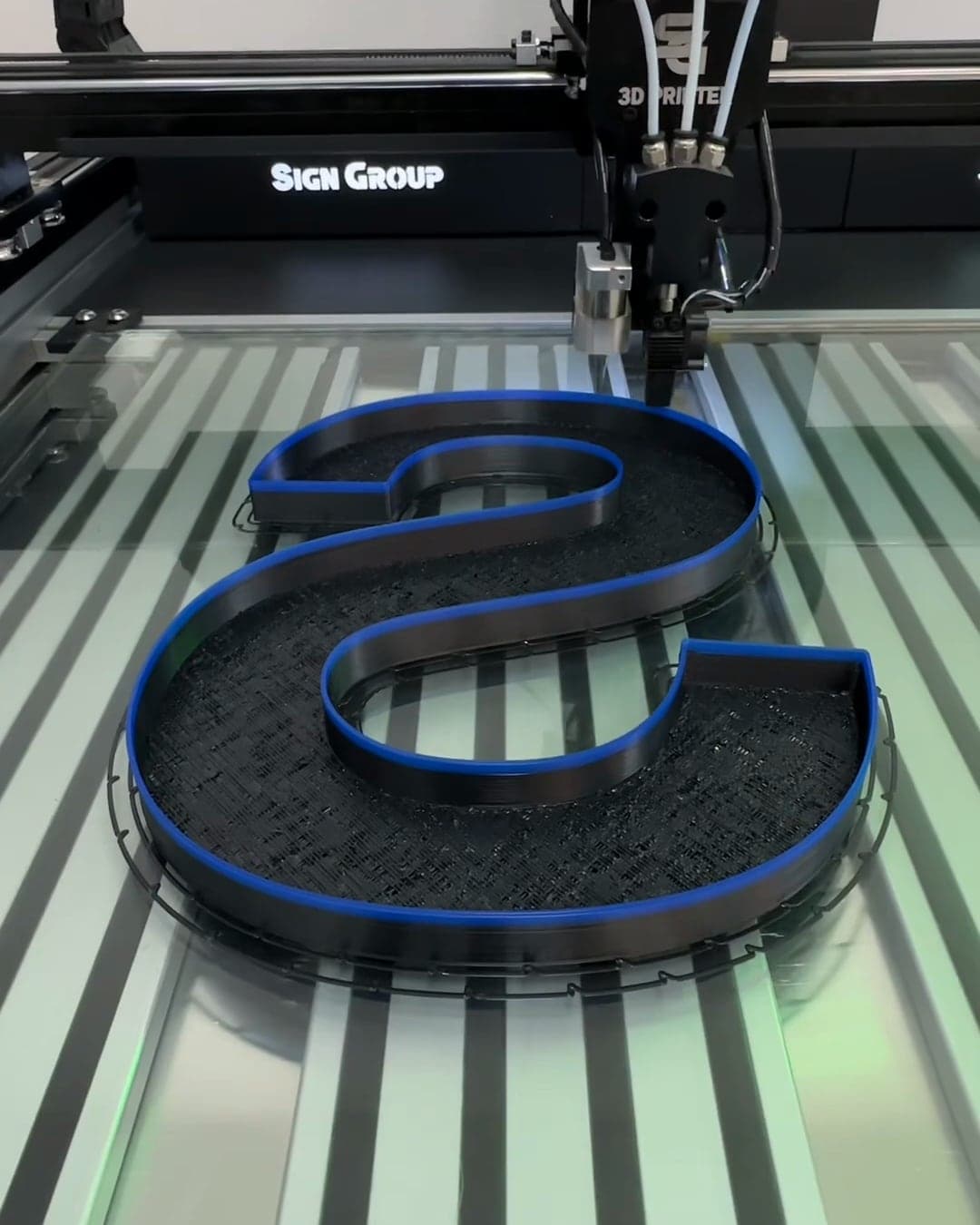 A black printed letter S with a blue-edged return, on the printer bed